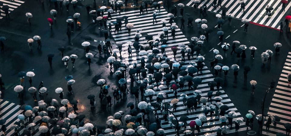 A large crowd of people crossing a street at a busy intersection.