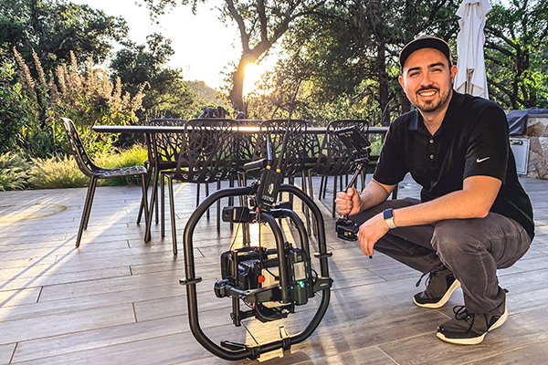 Pour's Executive Producer Dominic crouched on a wooden deck next to a professional camera rig mounted on a stabilizer.