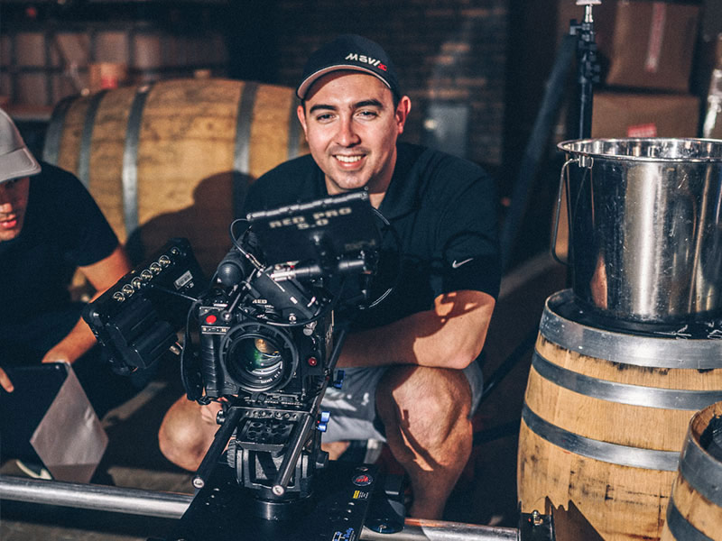 Pour video expert operates a RED cinema camera on a rig in a winery setting.