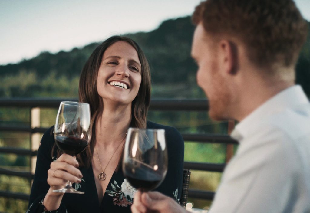 WineryHunt Case Study Still A woman and a man smile as they enjoy a glass of red wine.