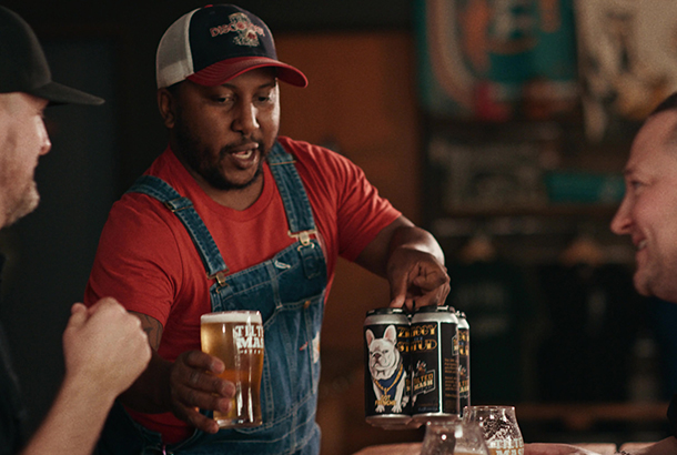 Tilted Mash Employees Testimonials A happy man serves a glass of beer to another man.