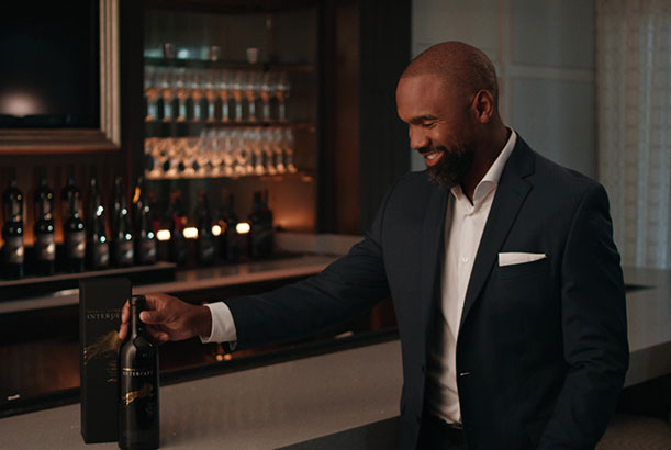 Charles Woodson’s Intercept Wines - NFL Hall of Fame Release Charles Woodson dressed in a suit holding a bottle of Intercept Wines.