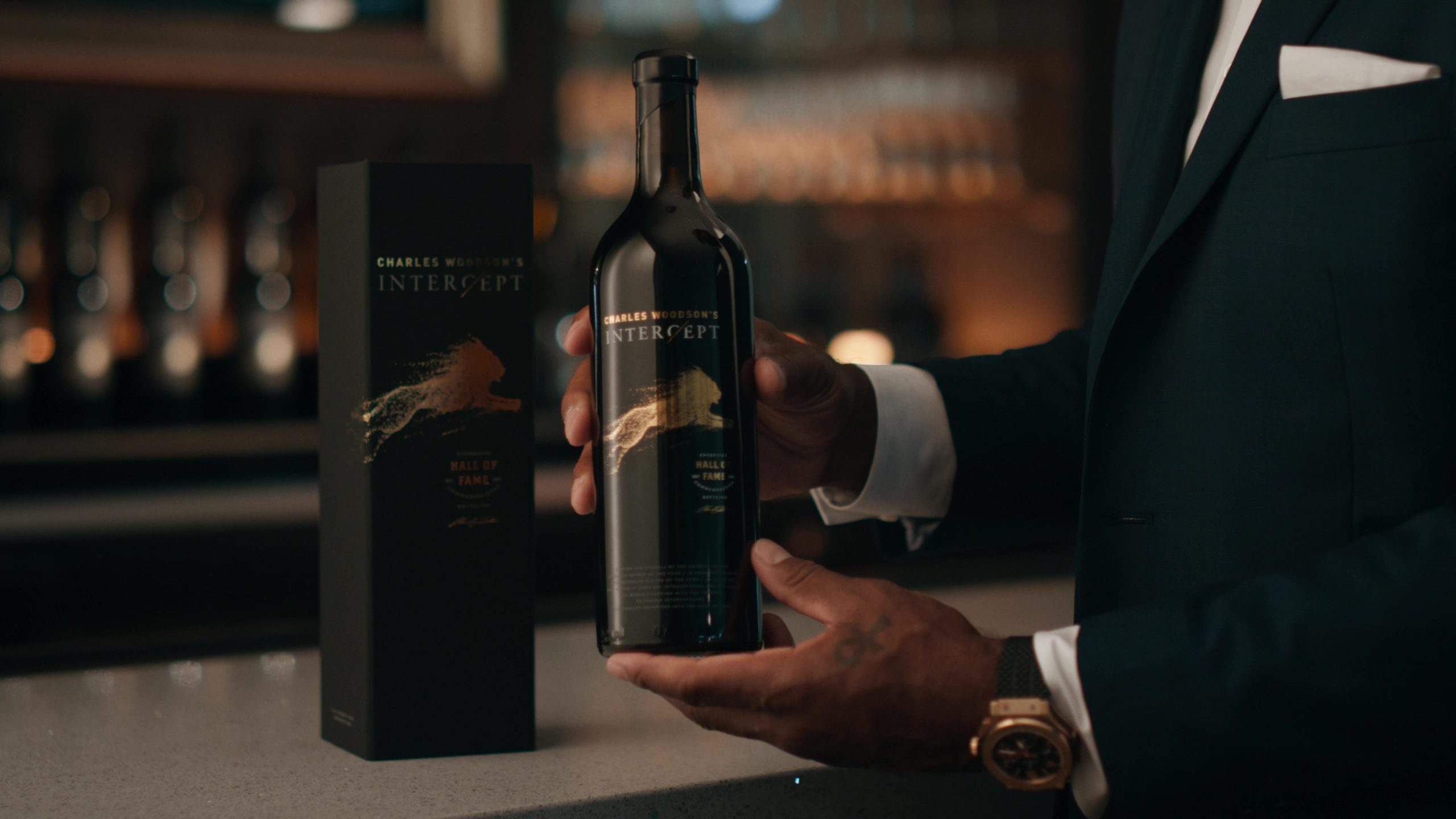 A bottle of wine labeled 'Charles Woodson's Intercept' being held by Charles Woodson.
