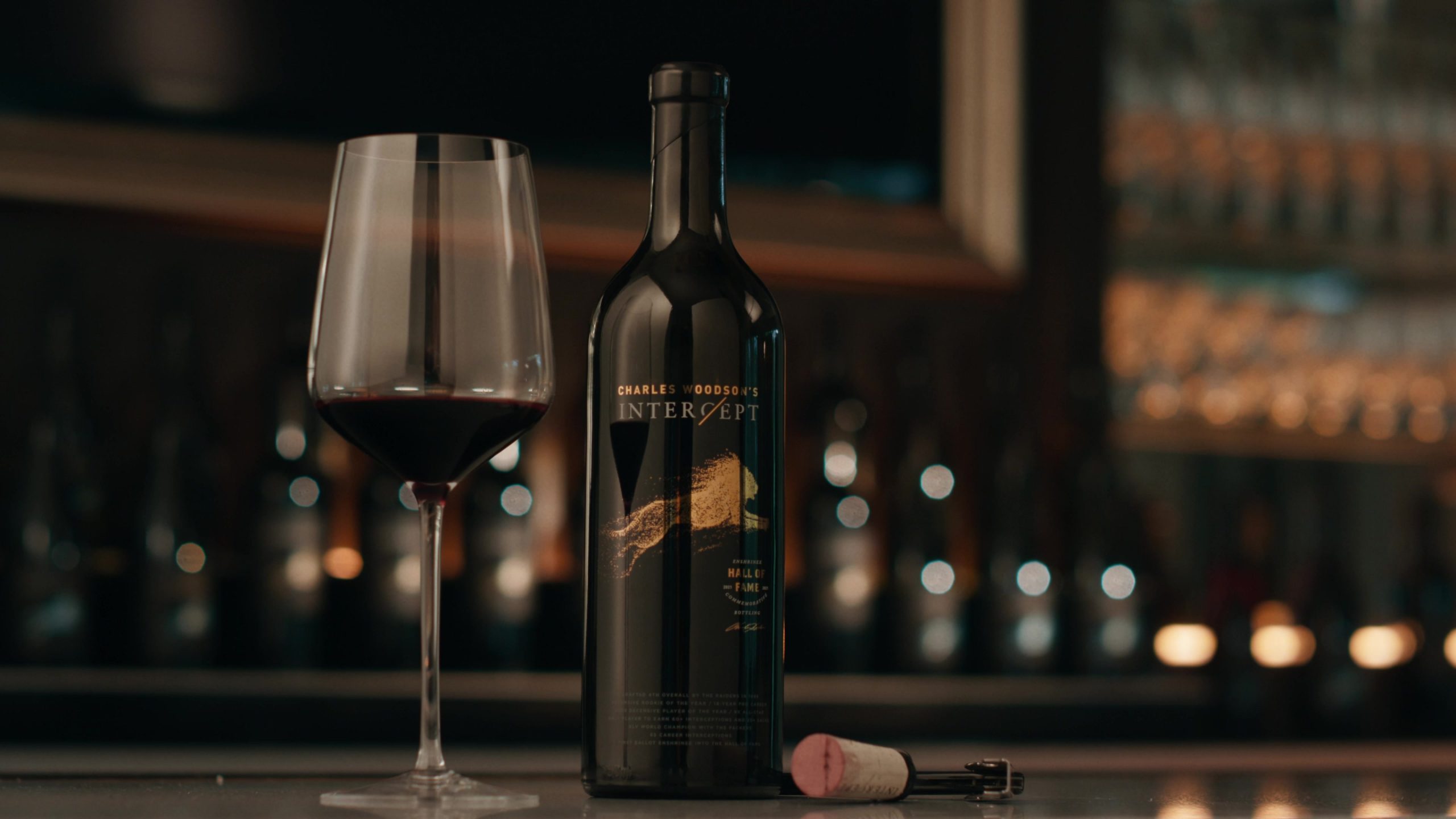 A bottle of wine labeled 'Charles Woodson's Intercept' next to a filled wine glass.