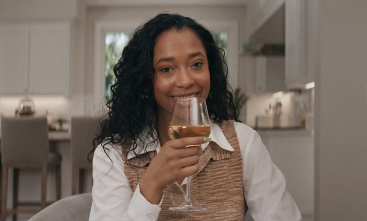 Smiling woman holding a glass of wine, promoting E40 Earl Stevens Wine Selection in a marketing campaign.