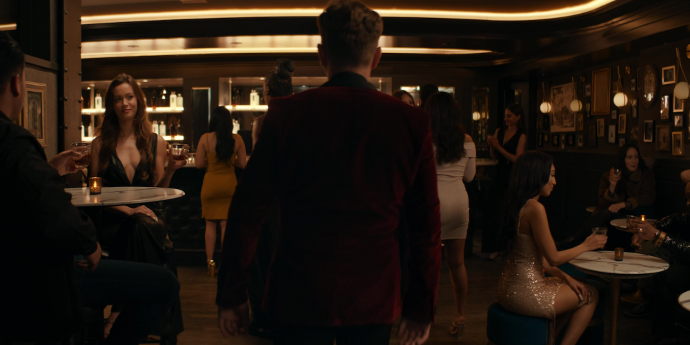 A man entering a bar full of people.